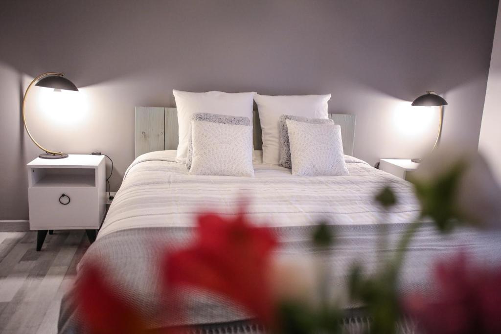 1 dormitorio con 1 cama blanca con almohadas blancas y flores rojas en Les Chambres d Hôtes de Valensole au pays des lavandes et proche des Gorges du Verdon, en Valensole