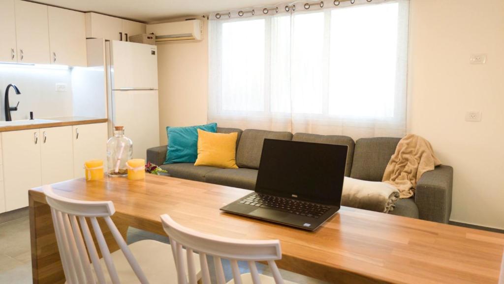 a laptop computer sitting on a wooden table in a kitchen at Primrose Boutique Apartment in Ashdod