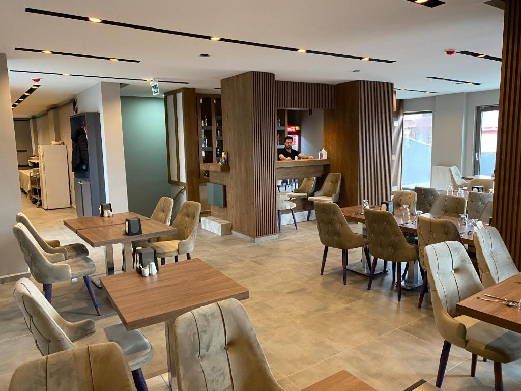 SarıkamısにあるSarıkamış Aras Otelの木製のテーブルと椅子、カウンターが備わるレストラン