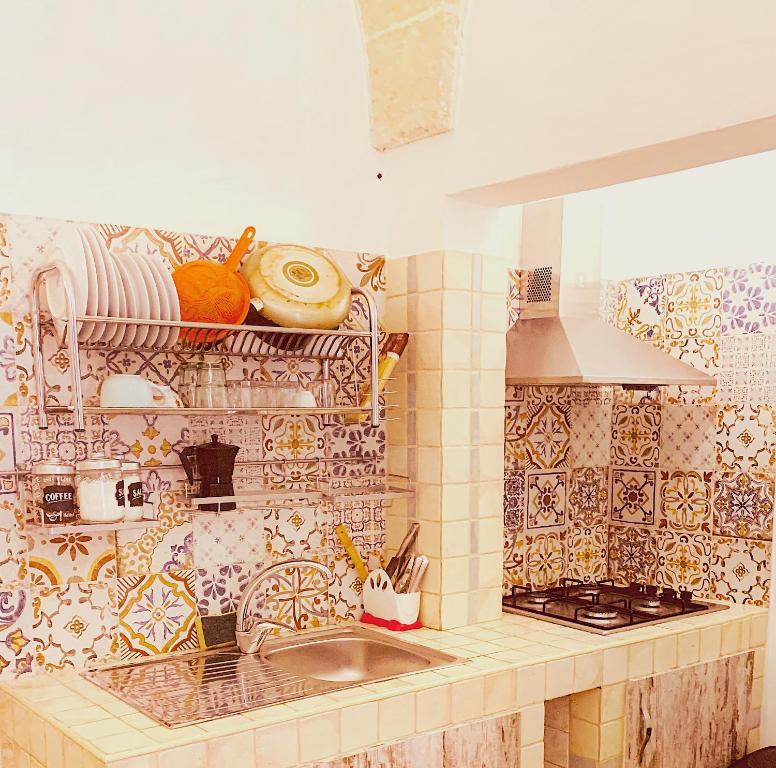 a kitchen with a sink and a tiled wall at Appartamento Bax 1 in Francavilla Fontana