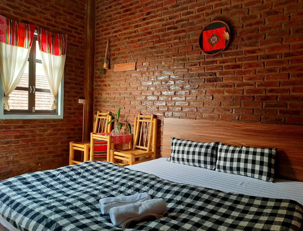 a bedroom with a bed and a brick wall at Hakuna Matata homestay Mai Châu in Mai Chau