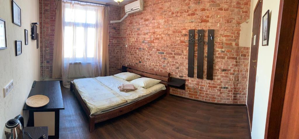 a bedroom with a bed and a brick wall at Kotsarskaya street 19 in Kharkiv