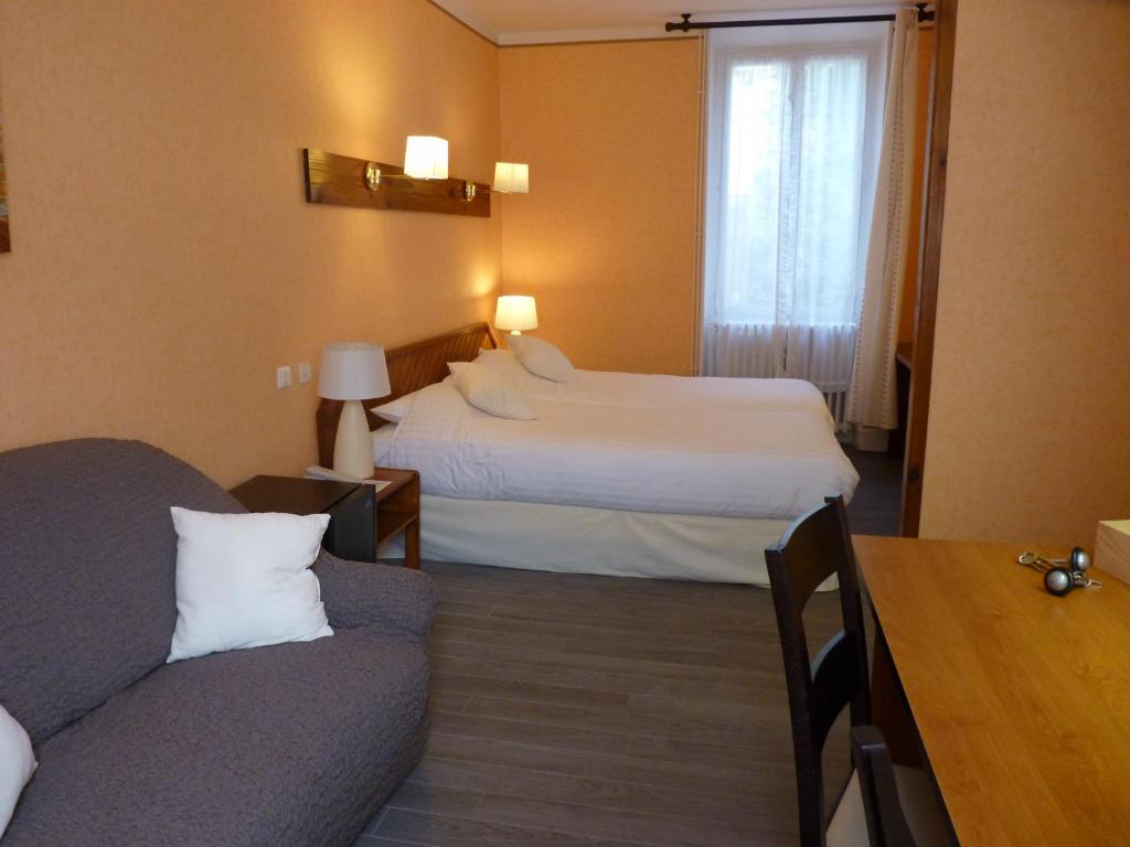 una camera d'albergo con due letti e un divano di Logis Hôtel Le Belle Rive a Najac