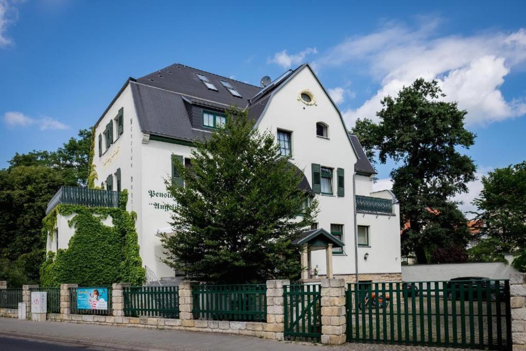 una casa blanca con un techo negro detrás de una valla en Villa Angelika, en Dresden