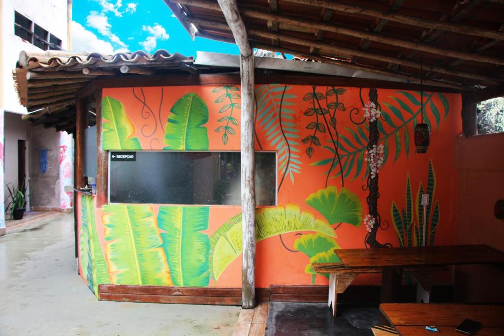 a wall with a mural of plants and a tv at Santo Hostel in Porto Seguro