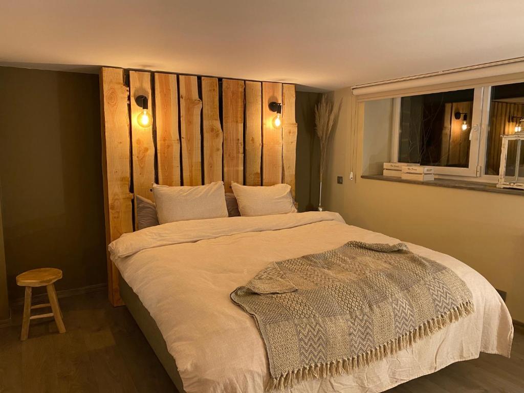 1 dormitorio con 1 cama grande y cabecero de madera en Le Retour aux Sources - Chambre d'Hôte chaleureuse et conviviale en Chaudfontaine