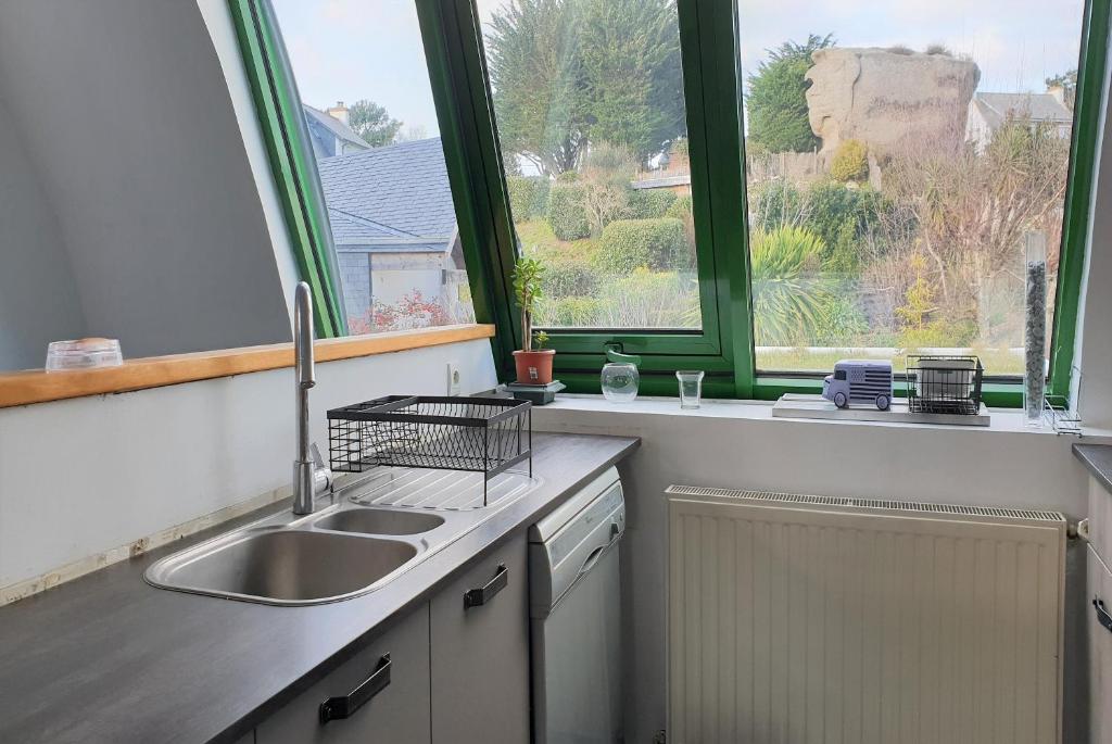 une cuisine avec un évier et une fenêtre dans l'établissement Maison 6 pers, avec jardin clos au centre de Trégastel, à 500m de la plage - Réf 179, à Trégastel