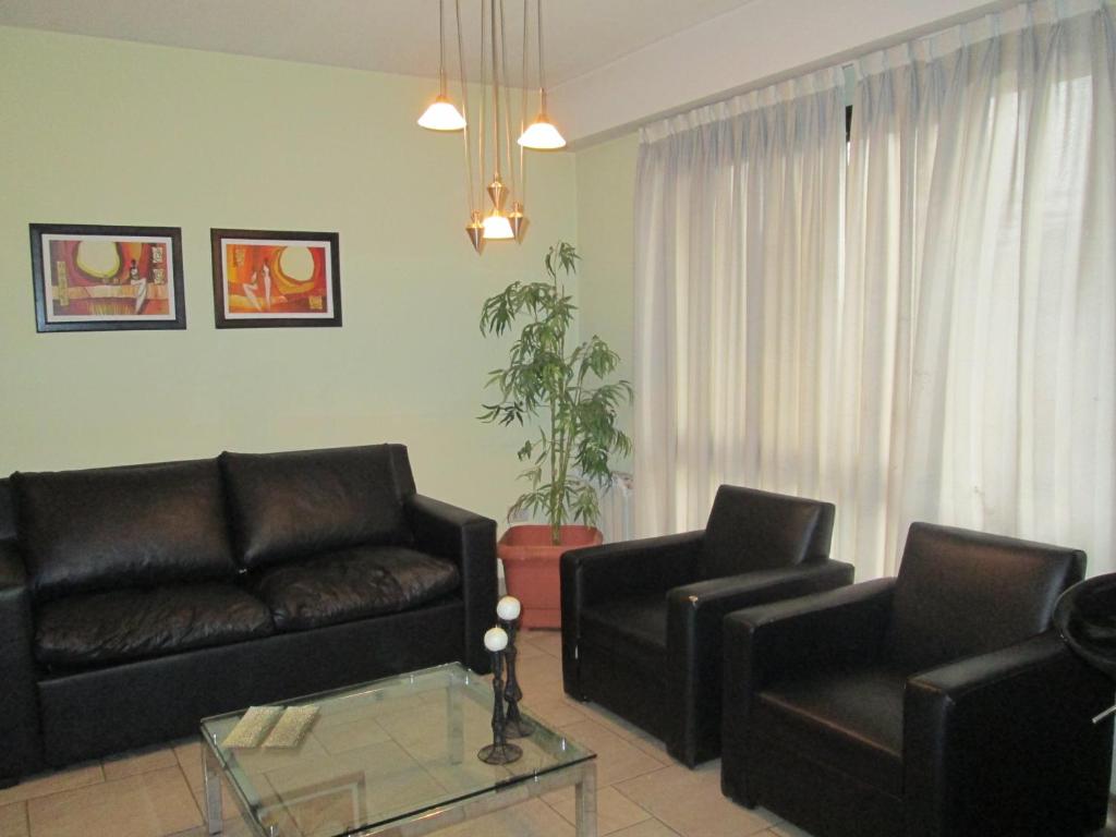 sala de estar con 2 sofás de cuero y mesa de cristal en Aires del Parque en Salta