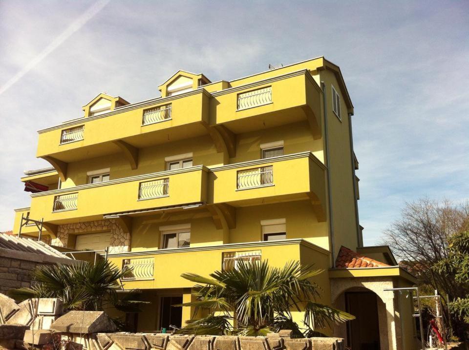 扎達爾的住宿－米里亞娜公寓酒店，一座棕榈树的黄色建筑