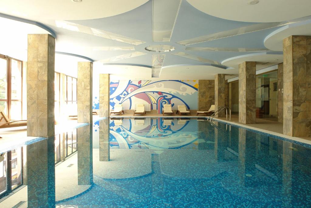 a pool in a building with a mural on the wall at Winslow Infinity Aparthotel in Bansko