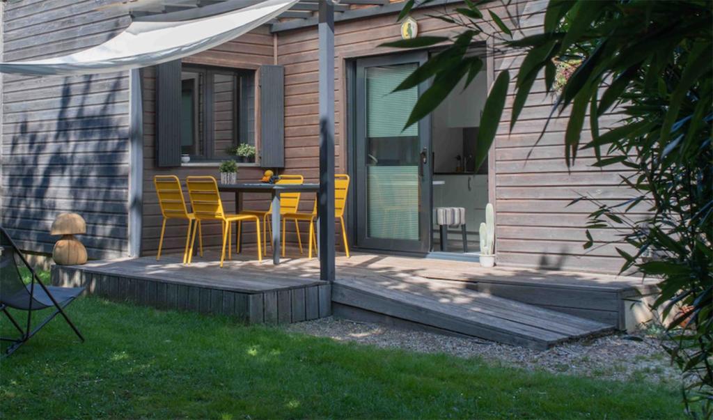 a patio with yellow chairs and a table on a house at L'Eden Weiss in Magny-les-Hameaux