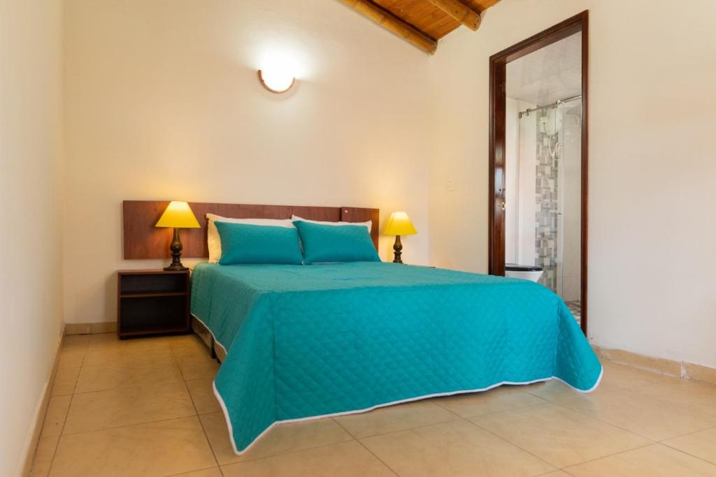 um quarto com uma grande cama azul e 2 candeeiros em hotel villa claudia em Nobsa