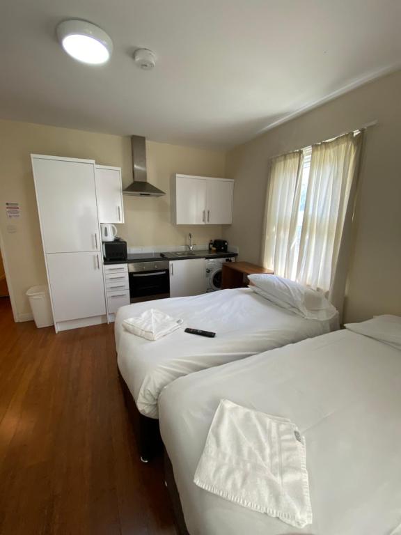 a hotel room with two beds and a kitchen at Contractors Guest House in High Wycombe