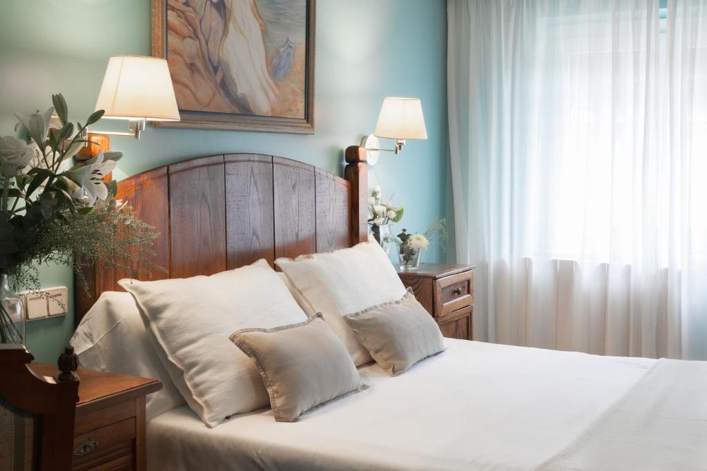 a bedroom with a bed with white sheets and pillows at La Galería in Donostia-San Sebastián