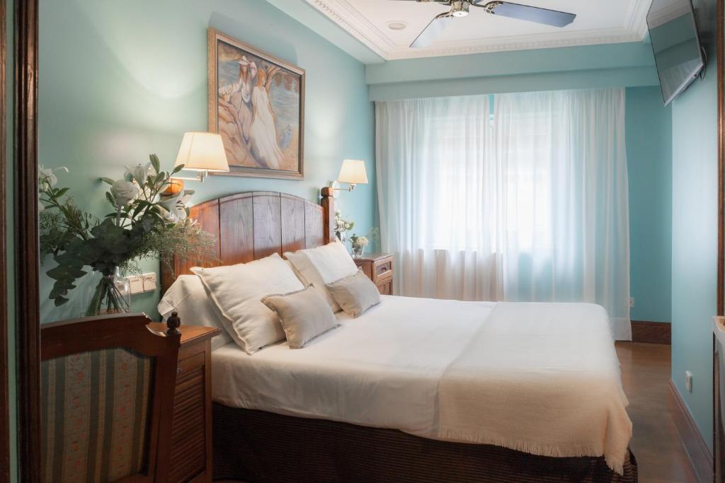 a bedroom with a bed with white sheets and a window at La Galería in Donostia-San Sebastián