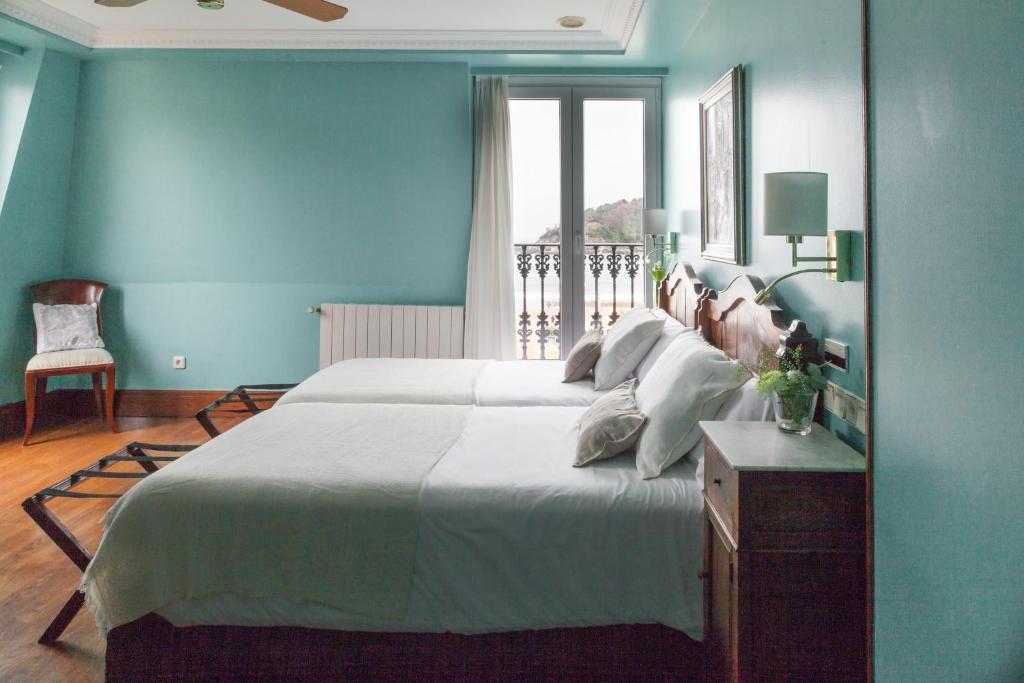 a blue bedroom with a large bed and a window at La Galería in Donostia-San Sebastián