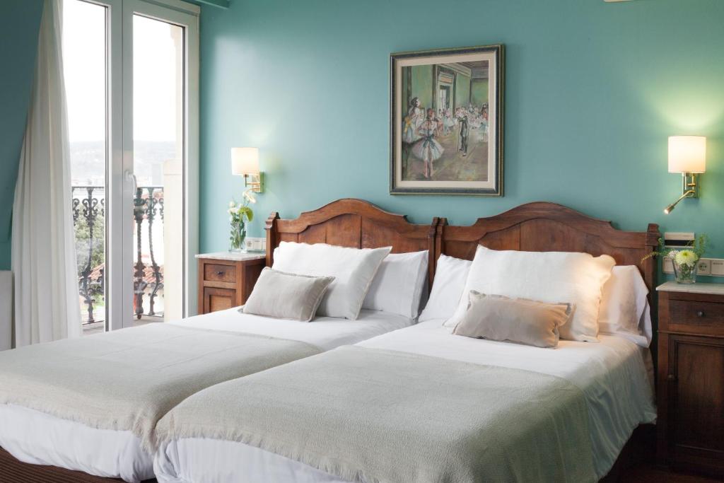 two beds in a room with blue walls at La Galería in Donostia-San Sebastián