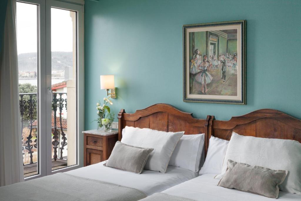 a blue bedroom with two beds and a painting on the wall at La Galería in Donostia-San Sebastián