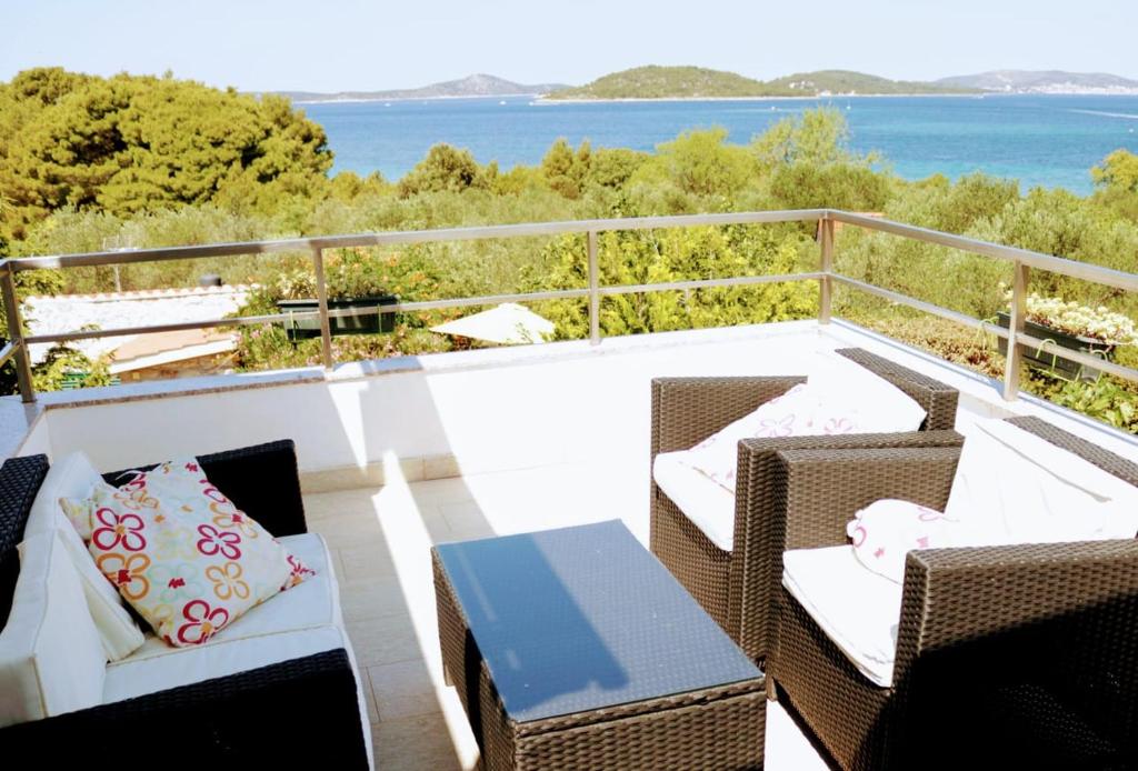 a balcony with wicker chairs and a table and the ocean at Holiday Home Subasic in Zlarin