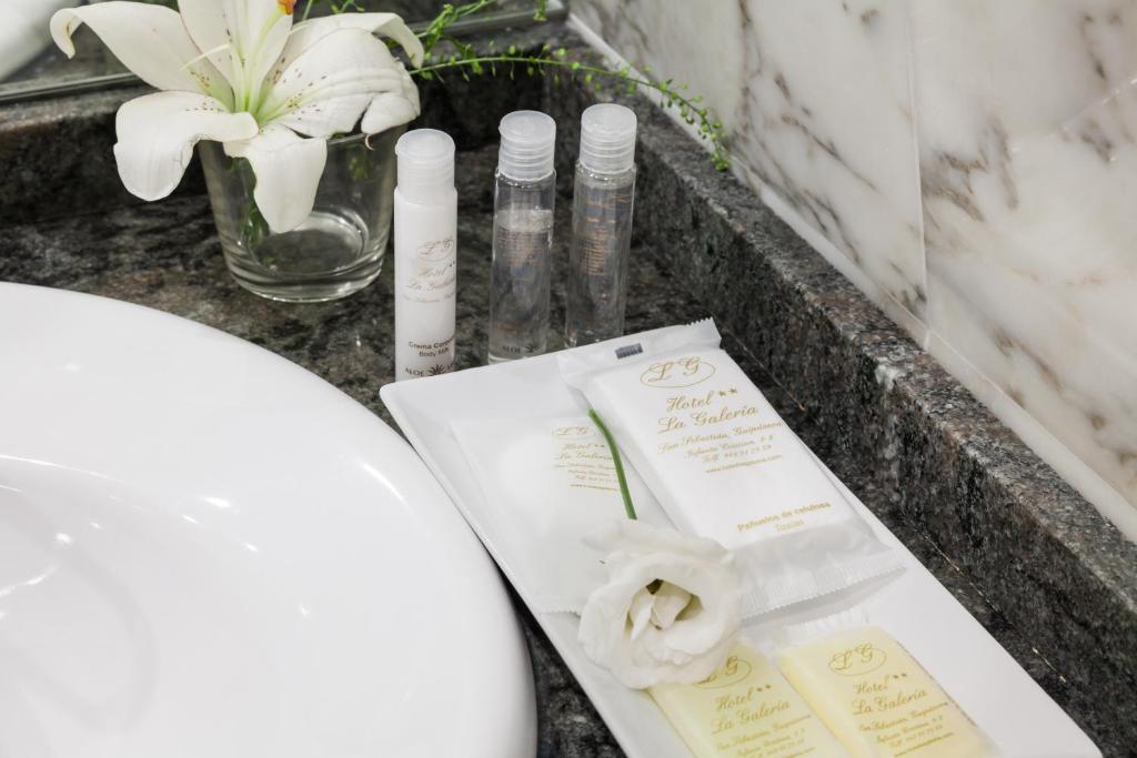 a bathroom counter with a spa kit and flowers at La Galería in Donostia-San Sebastián