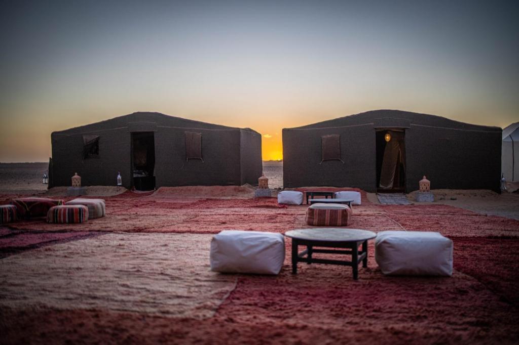 two tents in the desert with a sunset in the background at M'hamid Bivouac - Chez Naji in Mhamid