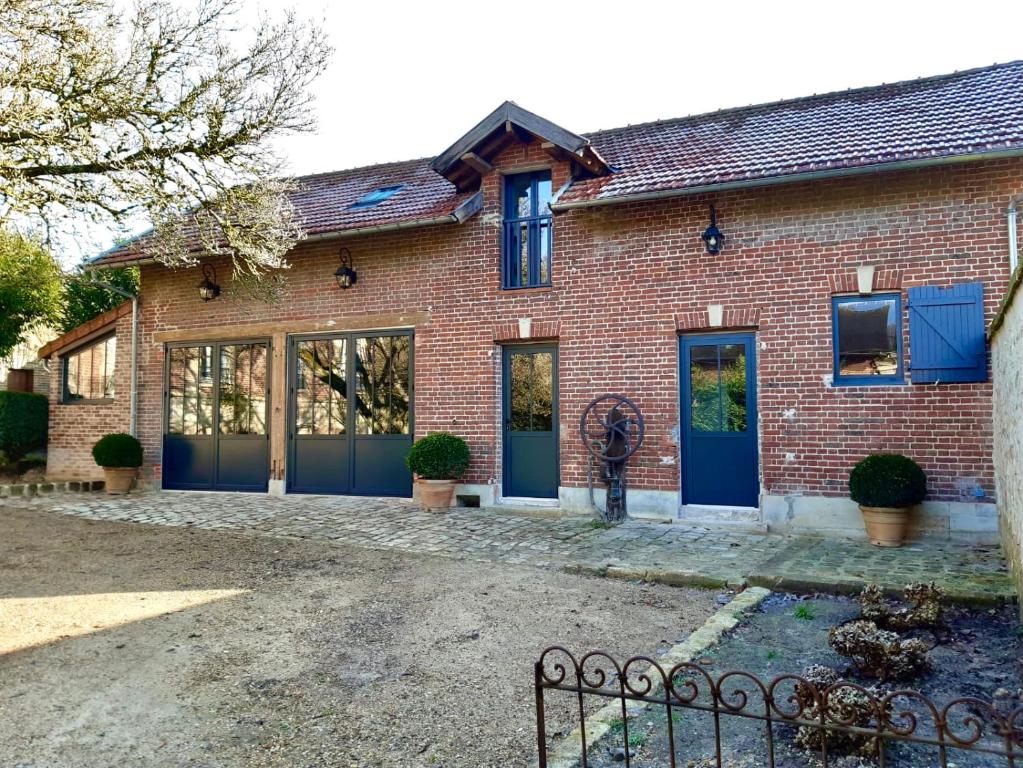 a brick house with blue doors and windows at L'Atelier des Magnolias in Aumont