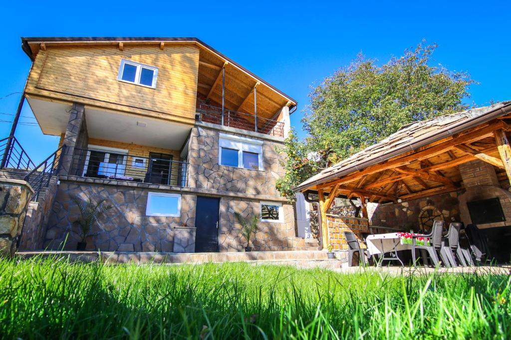 a large house with a wooden roof and a patio at Vila Nemir Zavojsko jezero in Pirot
