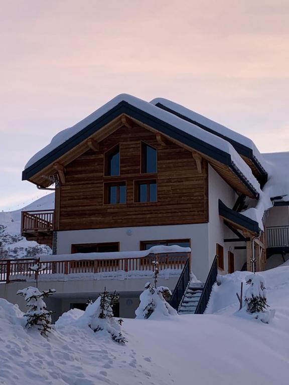 une maison en rondins avec de la neige sur le toit dans l'établissement La suite du skilodge, à La Toussuire