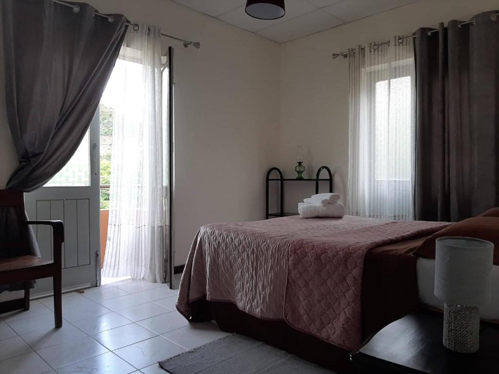 een slaapkamer met een bed en een groot raam bij Casa Pedrina in Ribeira Grande