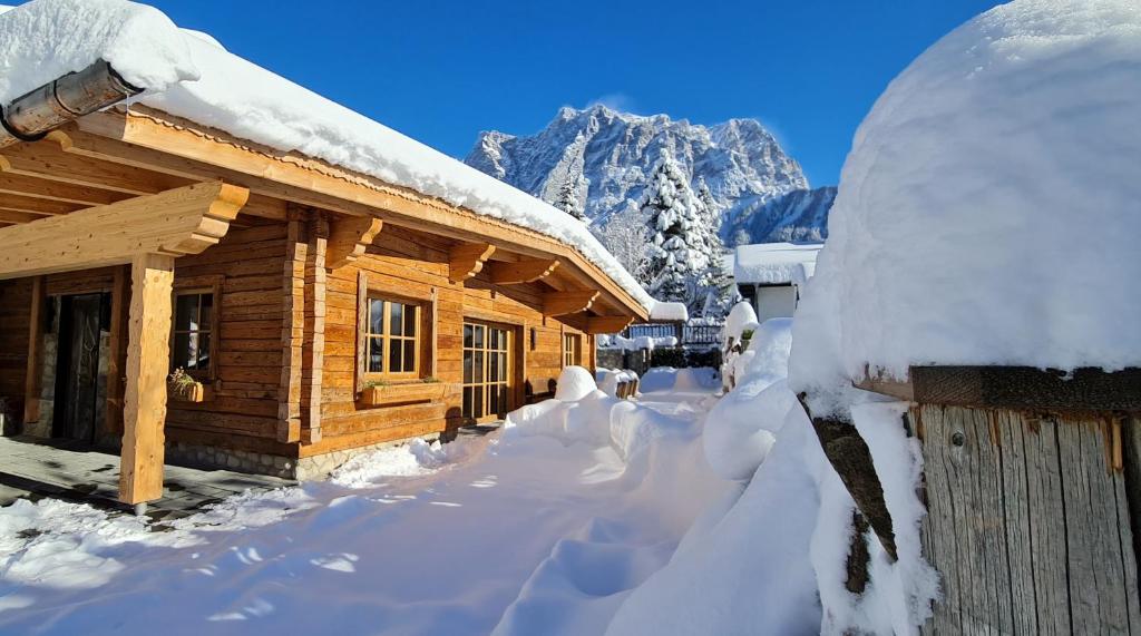 a log cabin covered in snow with a mountain in the background at Chalet Zugspitztraum in Ehrwald