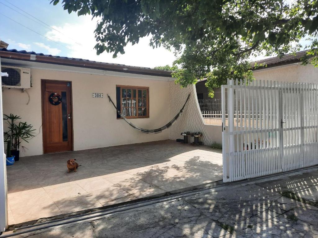 a dog sitting in front of a house with a fence at Casa da Karin in Torres