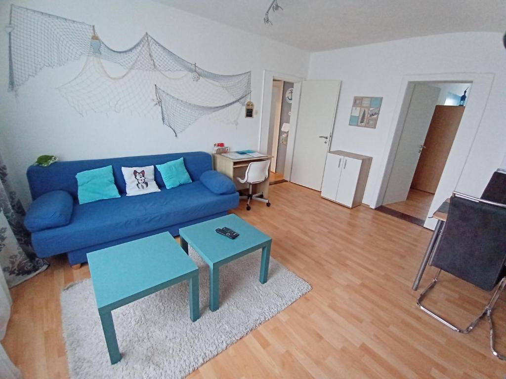 ein Wohnzimmer mit einem blauen Sofa und einem Tisch in der Unterkunft Ferienwohnung Maritim mit E-Bike Verleih in Wilhelmshaven