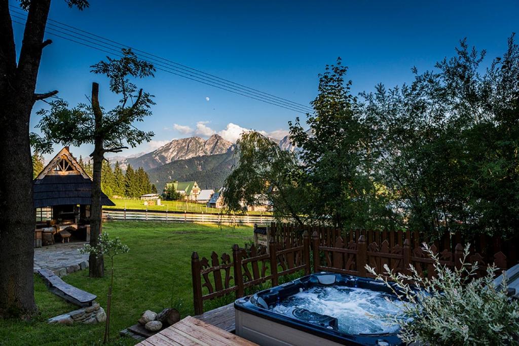 a hot tub in a yard with mountains in the background at Góralski Spa - Luksusowa willa z sauną i wanną z hydromasażem in Kościelisko