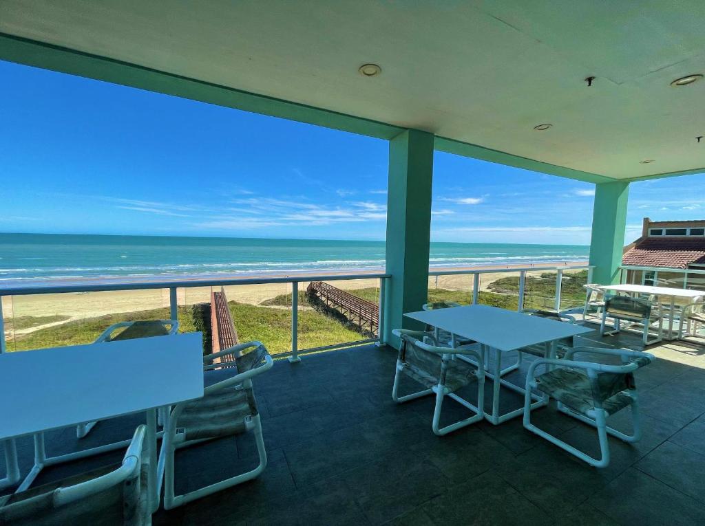 a balcony with tables and chairs and the ocean at 5 BEDROOM BEACHFRONT CONDO - 3rd Floor in South Padre Island