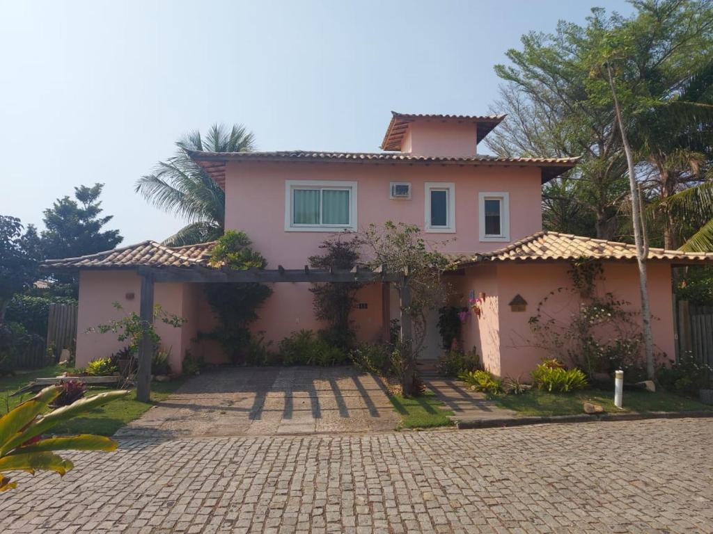una casa rosa con una entrada delante de ella en Linda Casa Búzios - 4 Suites - Piscina Exclusiva, en Búzios