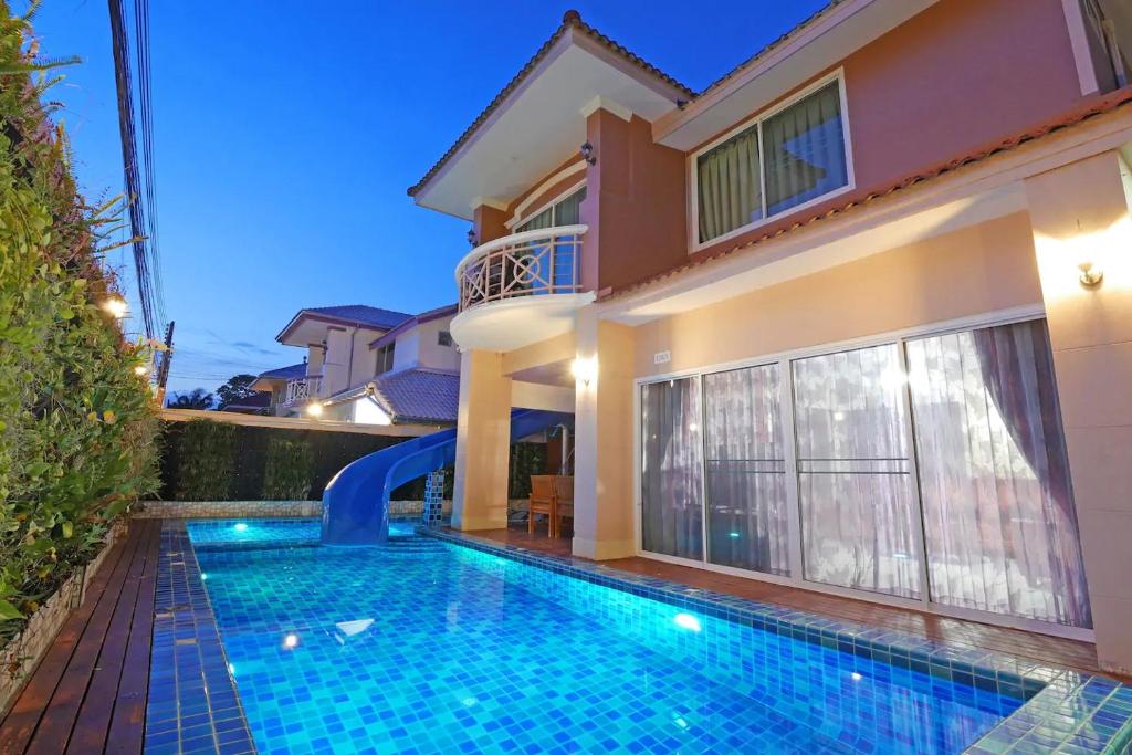 a villa with a swimming pool in front of a house at Pattaya Pool Villa in Jomtien Beach