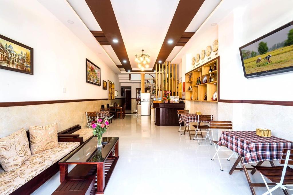 um átrio de um restaurante com um sofá e mesas em Miss Ten Homestay em Hoi An