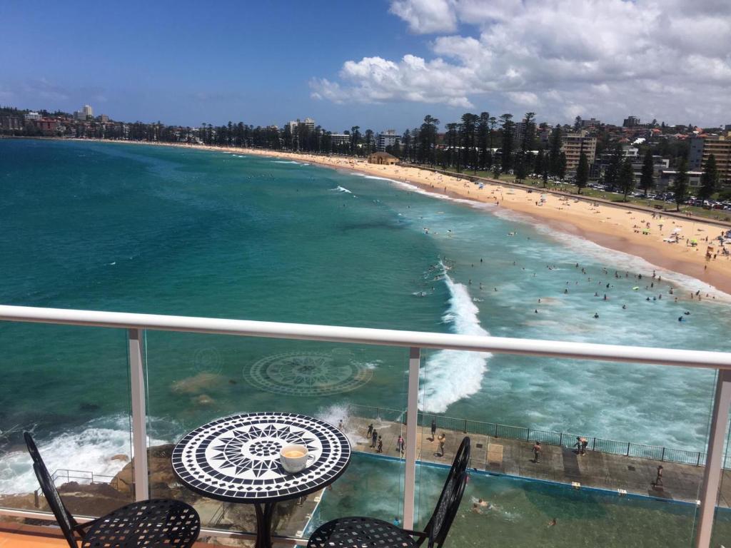 a balcony with a view of a beach and the ocean at Manly Waterfront Beach Stay in Queenscliff