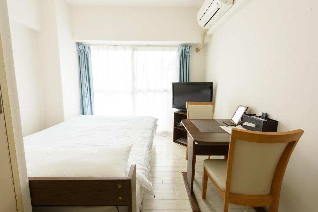 um pequeno quarto com uma cama e uma secretária com um computador em COCOSTAY Global Noboricho4F ココステイ グローバル ノボリチョウ4F em Hiroshima