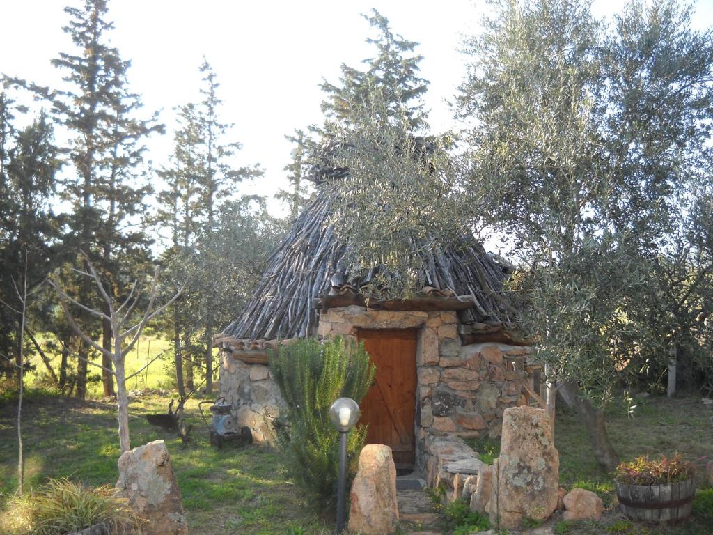 una pequeña casa de piedra con techo de paja en Munduge b&b, en Lotzorai
