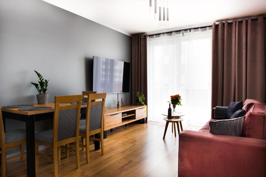 a living room with a dining room table and a television at Apartamenty Cypryjskie in Koszalin