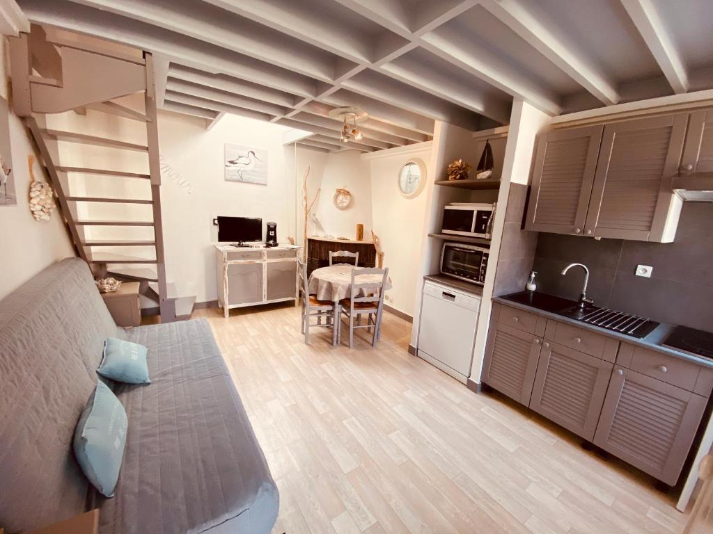 uma cozinha e sala de estar com um sofá e uma mesa em La Cabourgeaise em Cabourg