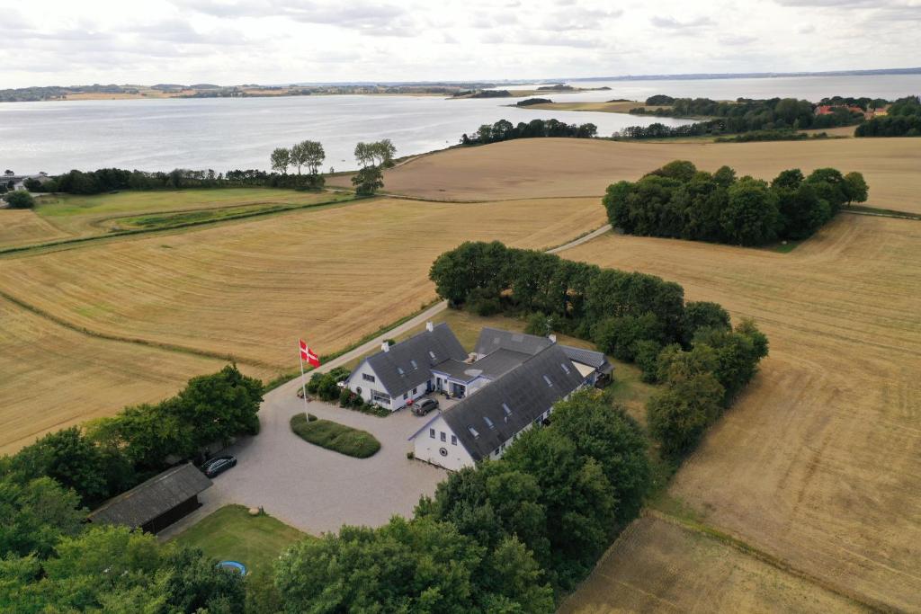 an aerial view of a house with a field and water at Rolsø Retreat in Knebel