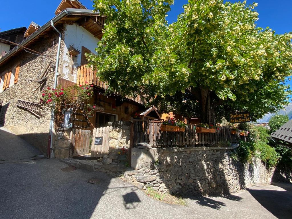 a building with a tree next to a fence at Auberge De La Forêt - Hôtel in Auris