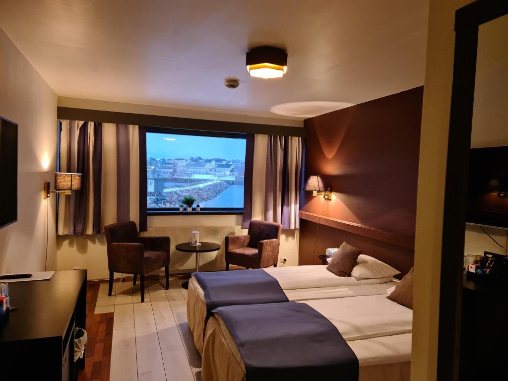 ヴァードーにあるVardø Hotelのベッドと大きな窓が備わるホテルルームです。