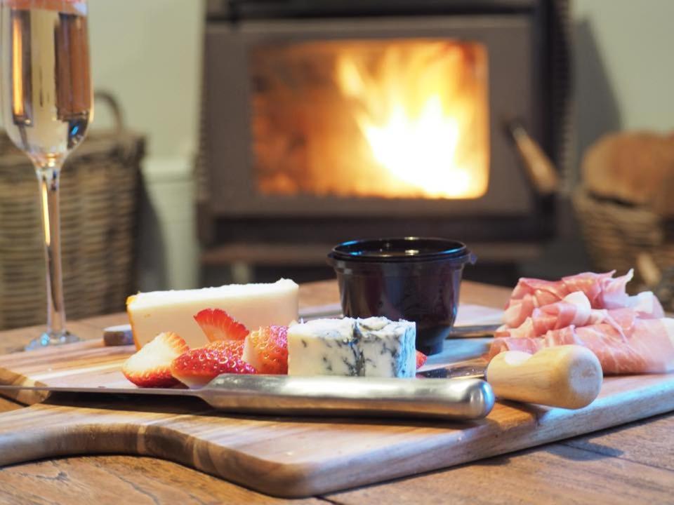 a wooden table with a plate of cheese and fruit at Lark Cottage in Burrawang