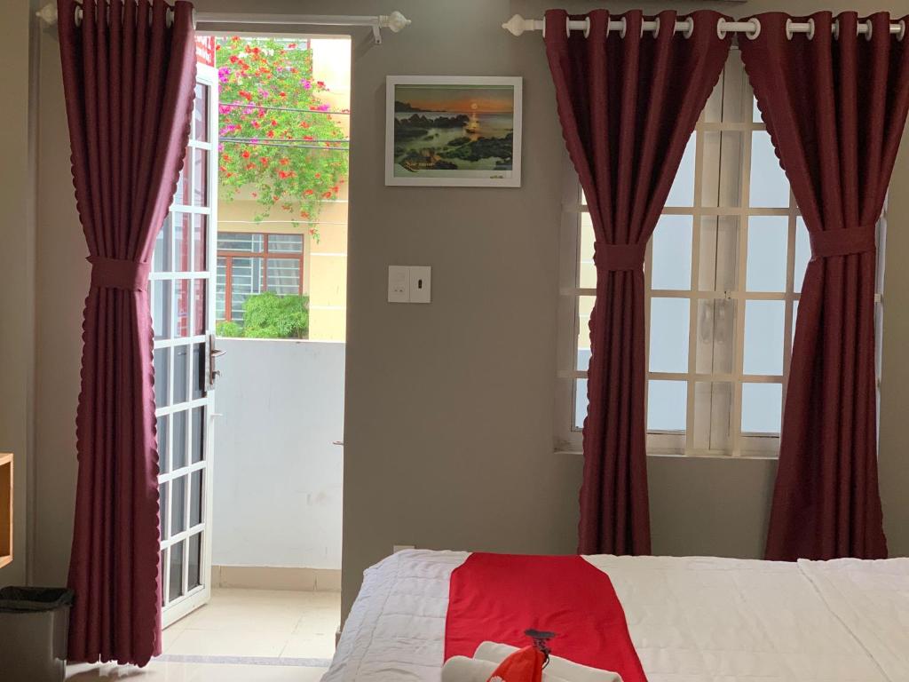 Schlafzimmer mit zwei großen Fenstern und roten Vorhängen in der Unterkunft Bờ Sông Hotel in Ho-Chi-Minh-Stadt