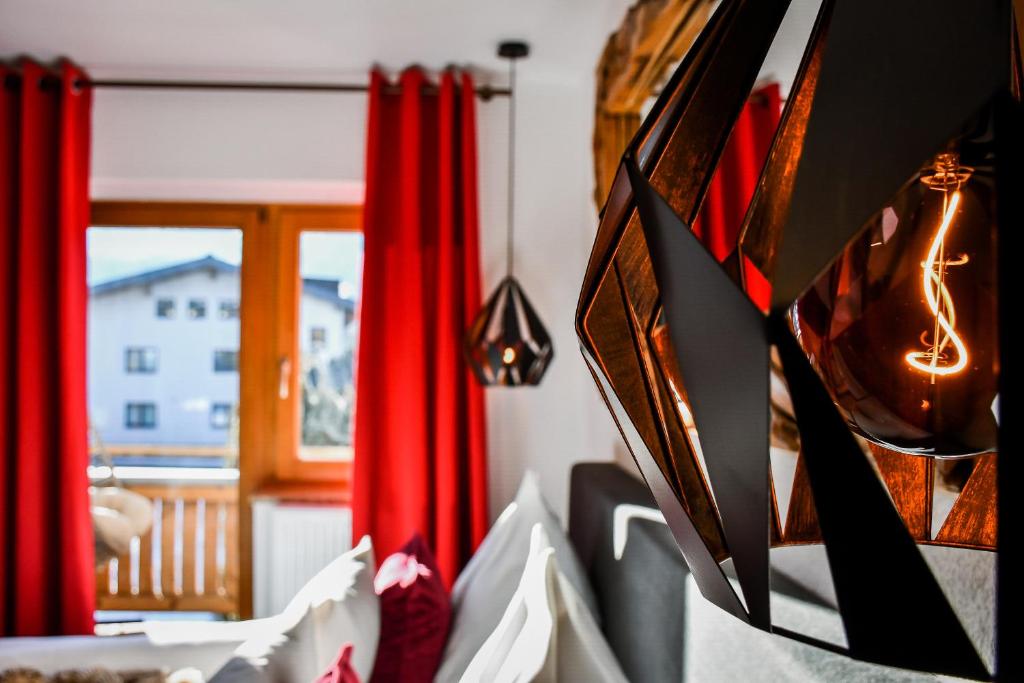 a room with red curtains and a window at Boutique Hotel Pinzgauerhof in Kaprun
