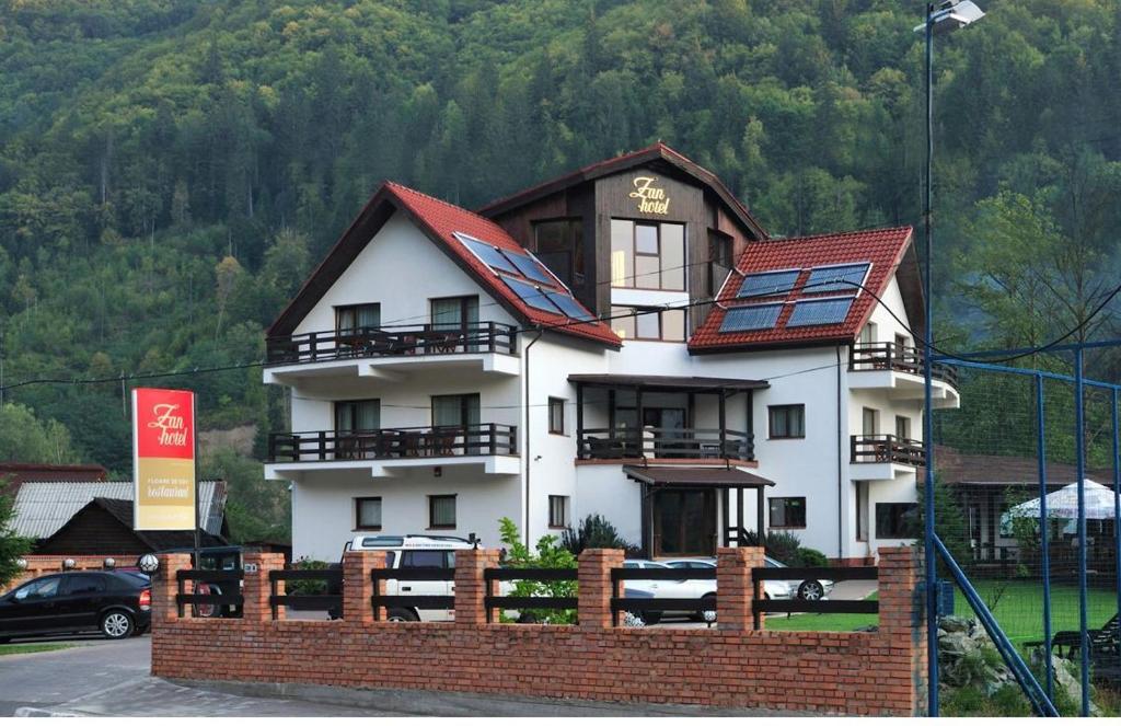 a large white building with a red roof at Zan Hotel in Voineasa