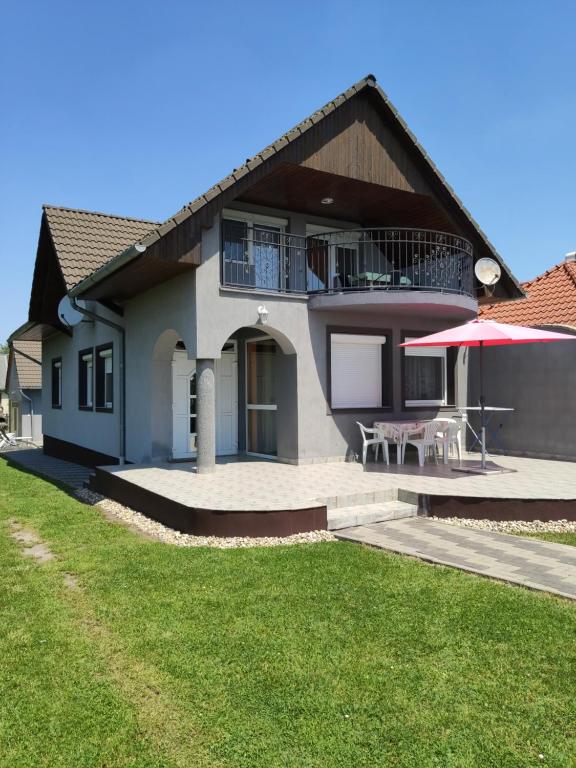 Cette maison dispose d'une terrasse avec une table et un parasol. dans l'établissement Zafír Nyaraló, à Balatonfenyves